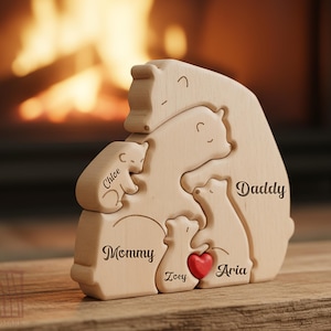 May include: A wooden puzzle featuring a family of bears, with each bear representing a family member. The names "Chloe", "Mommy", "Zoey", "Aria", and "Daddy" are engraved on the bears. A small red heart is included.