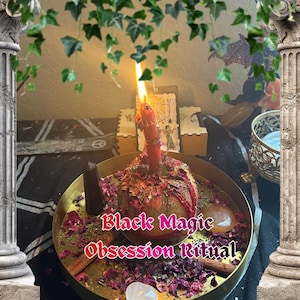 May include: A lit red candle sits atop a decorated sphere, surrounded by dried herbs and rose petals, on a gold-colored tray. The text "Black Magic Obsession Ritual" is displayed. The scene includes tarot cards and decorative elements.