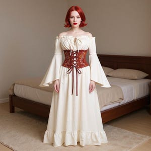 May include: An off-white, off-the-shoulder dress with long, bell sleeves and a ruffled hem. The dress features a brown corset with floral embroidery and a lace-up front. The dress is a medieval or renaissance style.