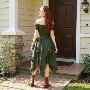 May include: An olive green off-the-shoulder dress with a tiered, asymmetrical hemline. The dress features a fitted bodice and short sleeves. The model is wearing brown boots. The background includes a house with a brown door and a brick walkway.