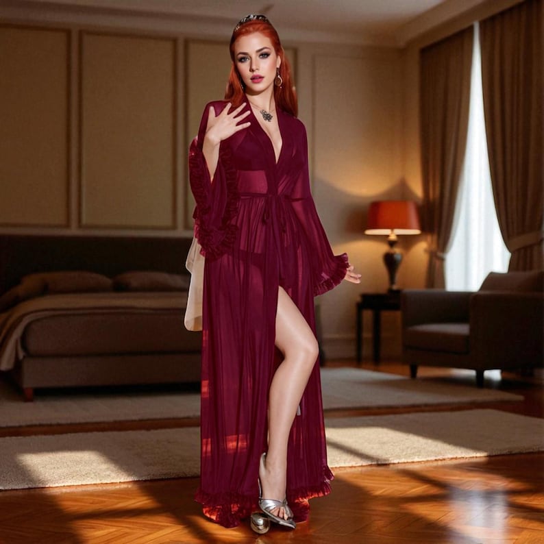 May include: A long, flowing burgundy robe with a high slit, ruffled sleeves, and a matching belt. The sheer fabric reveals a glimpse of lingerie. The robe is worn with silver sandals, creating an elegant and luxurious look.