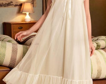 Può includere: Una camicia da notte color crema con scollatura quadrata e maniche a cappuccio arricciate. La camicia da notte presenta un fiocco di nastro sul busto e un orlo arricciato. Il tessuto sembra essere un materiale leggero e semitrasparente.