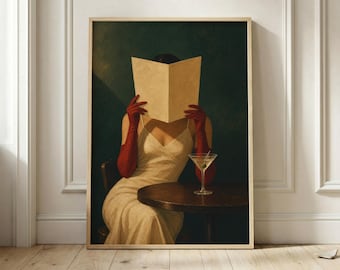 Puede incluir: Una lámina de arte enmarcada que muestra a una figura con un vestido lencero color crema y guantes rojos largos, sosteniendo un libro abierto sobre su rostro. Una copa de martini descansa sobre una mesa de madera oscura frente a la figura.