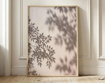 Op de afbeelding: Een rechthoekige wandkunstprint in een lichthouten lijst met een zachte beige achtergrond en de donkerbruine schaduw van boombladeren die op het oppervlak valt, waardoor een gelaagd botanisch patroon ontstaat dat de hele verticale compositie vult.