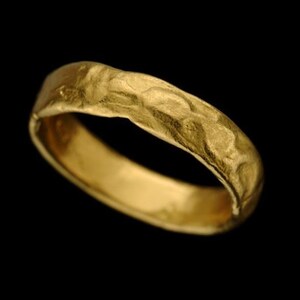 May include: A gold band ring with a textured surface.