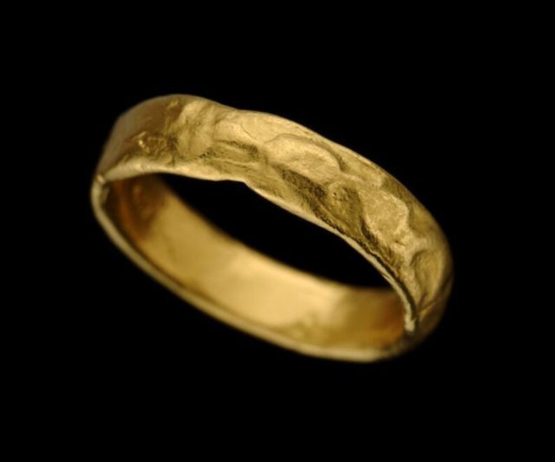 May include: A gold band ring with a textured surface.