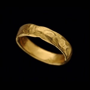 May include: A simple gold band ring with a textured surface.