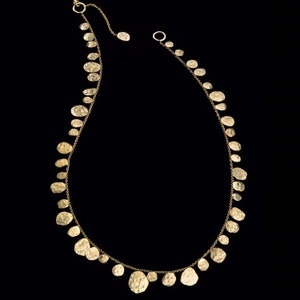 May include: A gold necklace with a delicate chain and a series of hammered, round pendants. The pendants are of varying sizes and are arranged in a cascading pattern.