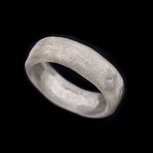 May include: A simple silver band ring with a smooth, slightly textured surface.