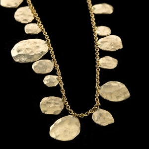 May include: A gold necklace with a chain and multiple round, hammered metal pendants.