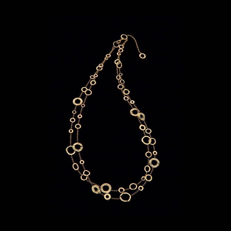 May include: A gold necklace with a delicate chain and multiple circular pendants of varying sizes. The necklace is layered and has a simple, elegant design.
