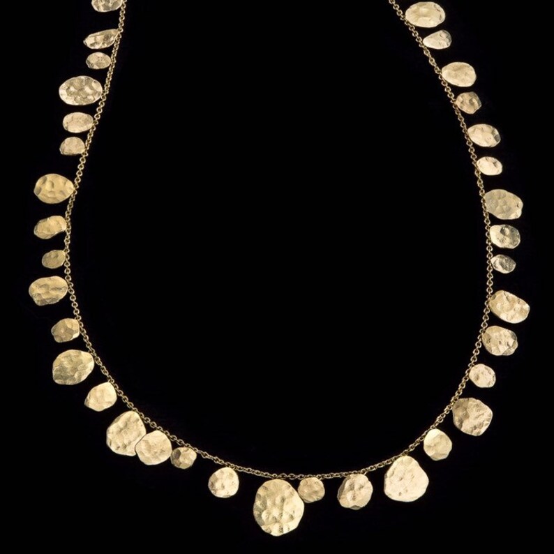May include: A gold necklace with a chain and multiple hammered gold discs hanging from it.