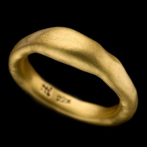 May include: A simple gold band ring with a smooth, slightly irregular surface. The ring is marked with "22K" on the inside.