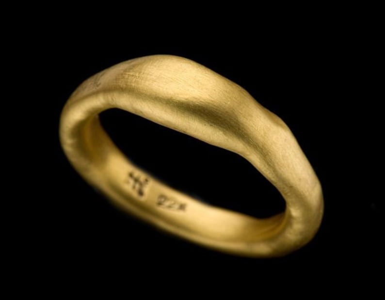 May include: A simple gold band ring with a smooth, slightly irregular surface. The ring is marked with "22K" on the inside.