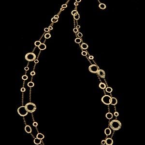 May include: A gold necklace with a double strand of hammered metal circles of varying sizes.