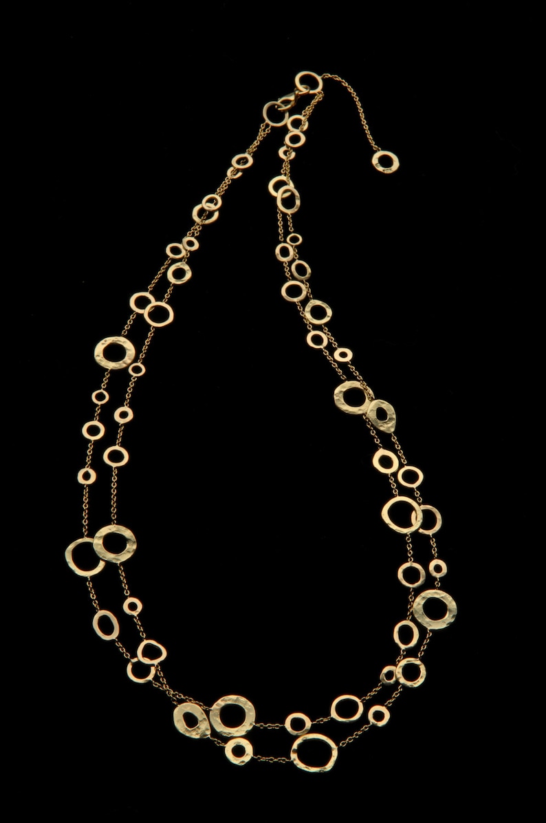May include: A gold necklace with a double strand of hammered metal circles of varying sizes.