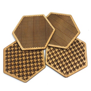 May include: Four hexagonal wooden coasters with different geometric patterns. Two coasters feature a herringbone pattern and two coasters feature a houndstooth pattern.