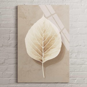 May include: A rectangular canvas print featuring a large, stylized leaf in shades of beige and brown. The leaf's veins are detailed with white lines, set against a neutral background. The artwork is mounted on a white brick wall.