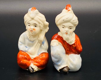 Könnte beinhalten: Zwei Keramikfiguren von Menschen, die Turbane und traditionelle Kleidung tragen. Die Figuren sind in Weiß-, Rot- und Blautönen bemalt.