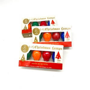 Pode incluir: Três pacotes de lâmpadas de Natal C-7 1/2. Cada pacote contém quatro lâmpadas nas cores vermelho, verde, azul e laranja. Os pacotes são etiquetados com "C-7 1/2 Christmas Lamps" e "120 Volts".