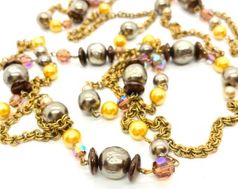 May include: A long gold chain necklace with multiple strands of beads. The beads are a mix of gold, brown, and iridescent colors.