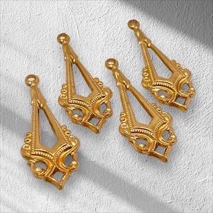 May include: Four gold-colored, ornate earring components. Each component has a teardrop shape with a loop at the top for attachment. The design features intricate filigree and decorative elements, suitable for jewelry making.