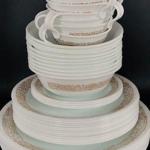 May include: A stack of white ceramic bowls with a brown floral pattern. The bowls are nested together and are arranged in a pyramid shape.