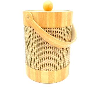 May include: A woven wicker and wood ice bucket with a wooden lid and handle. The bucket is light brown and has a woven pattern.