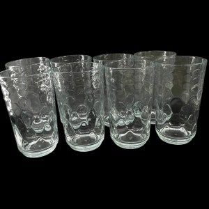 Puede incluir: Juego de seis vasos transparentes de vidrio con una superficie texturizada y con burbujas. Los vasos están vacíos y dispuestos en fila.