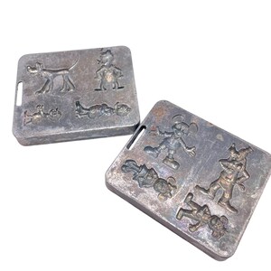 Könnte beinhalten: Zwei Vintage-Metallformen mit Disney-Figuren. Eine Form hat Pluto und Donald Duck, die andere Micky Maus und Goofy. Die Formen sind rechteckig mit Charakterprägungen.