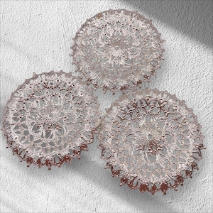 May include: Three silver decorative plates with a lacy design. The plates are round and have a delicate, intricate pattern.