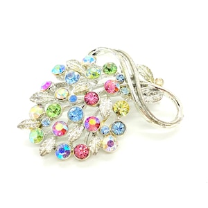 May include: A silver brooch with a floral design featuring a cluster of colorful rhinestones in shades of pink, blue, green, and yellow.