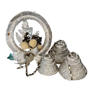 Pode incluir: Uma grinalda de Natal prateada com folhas decorativas, bagas e um laço. Acompanham a grinalda três sinos prateados com detalhes de contas. Estes são provavelmente decorações de férias vintage.