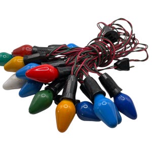 Pode incluir: Uma corda de luzes de Natal vintage com lâmpadas coloridas. As lâmpadas são vermelhas, verdes, azuis, amarelas, laranja e brancas. As luzes são enfiadas juntas com um fio preto.