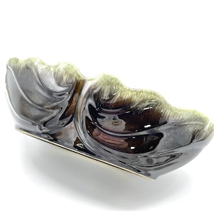 May include: A large, black and green ceramic bowl with a wavy, organic design. The bowl has a glossy finish and is perfect for serving or displaying.