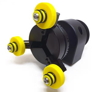 May include: A black rotary table with three yellow wheels. The wheels have black rubber rings around them. The table is mounted on a black base.