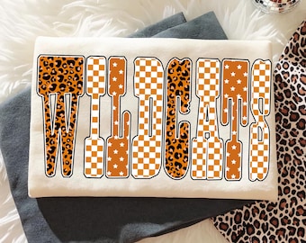 PNG dos Wildcats: Letras retrô com estampa de leopardo e estrela em padrão xadrez, design para camiseta de dia de jogo com espírito escolar, download digital para sublimação universitária.