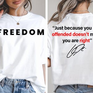 Puede incluir: Camiseta blanca con la palabra "FREEDOM" en letras negras grandes en la parte delantera. La parte posterior de la camiseta presenta la cita, "Just because you are offended doesn't mean you are right" en negro y rojo.