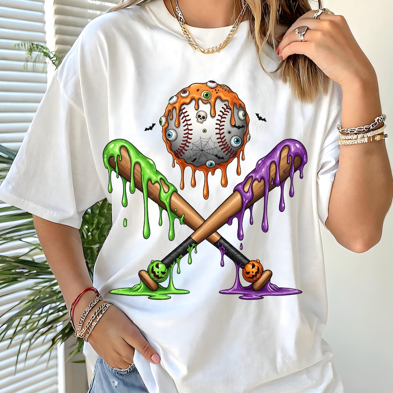 K&ouml;nnte beinhalten: Wei&szlig;es T-Shirt mit einem Halloween-Motiv. Die Grafik zeigt einen Baseball mit tropfendem orangefarbenem Schleim, Aug&auml;pfeln und einem Spinnennetz, gekreuzte Baseballschl&auml;ger mit gr&uuml;nem und lila tropfendem Schleim und kleine Flederm&auml;use.