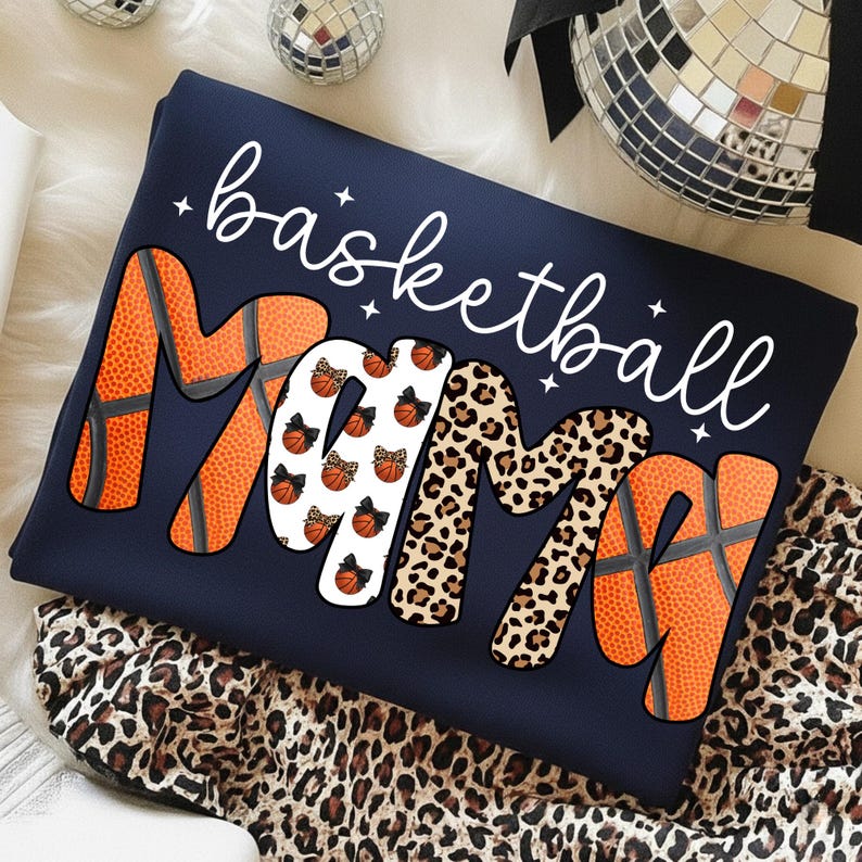 May include: Navy blue sweatshirt with the words "basketball Mama" in white script. The letters "M" and "A" are orange basketballs, the second "M" is leopard print, and the middle "M" has basketballs with bows.