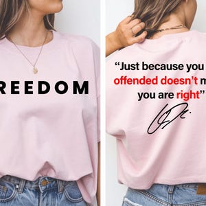 Puede incluir: Una camiseta rosa claro con la palabra "FREEDOM" en letras negras grandes. La parte trasera de la camiseta tiene la cita "Just because you are offended doesn't mean you are right" en texto negro y rojo, con una firma.