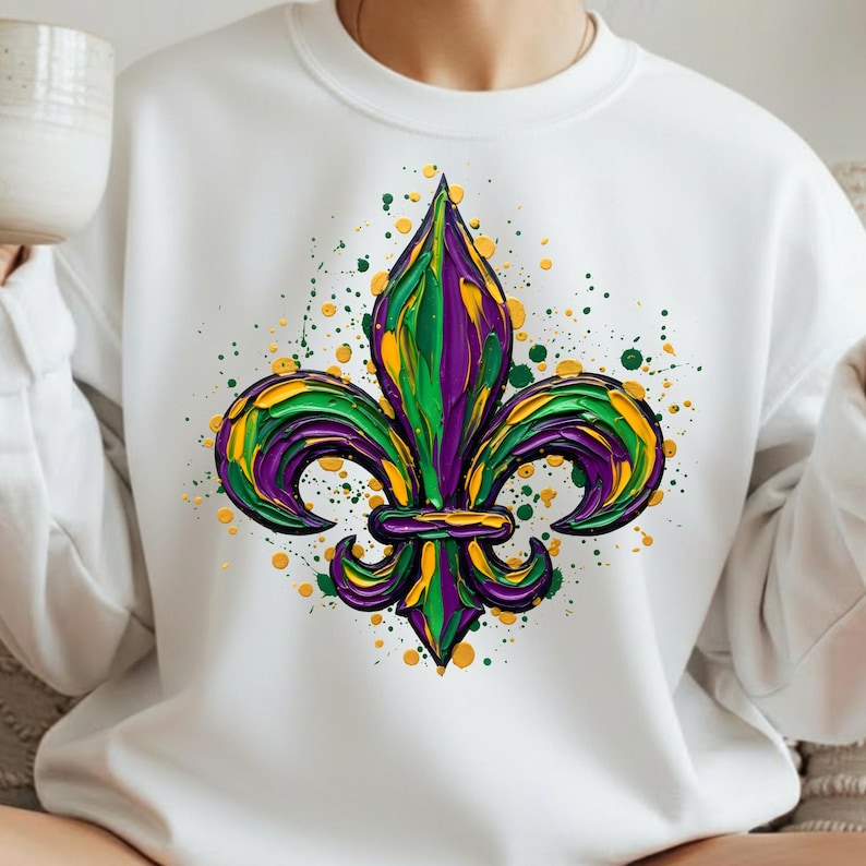 May include: White sweatshirt with a colourful fleur-de-lis design. The image displays a textured fleur-de-lis in green, purple, and yellow, with paint splatter details. A fashionable and artistic garment.