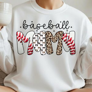 May include: White sweatshirt with the words "baseball Mama" in a playful design. The word "Mama" features baseball stitching, bow patterns, and leopard print. The word "baseball" is in a cursive font.