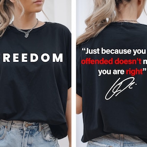 May include: Black t-shirt with the word "FREEDOM" in large white capital letters on the front. The back of the shirt has the quote "Just because you are offended doesn't mean you are right" in white and red text, with a signature.