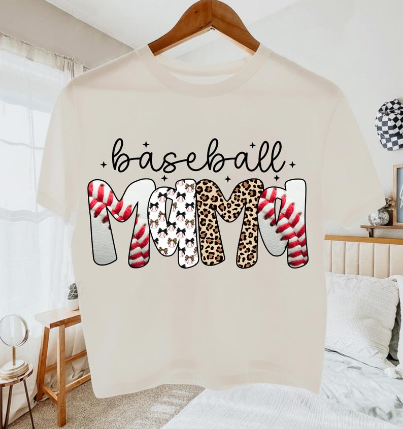 May include: Cream-colored t-shirt with the words "baseball mom" in a playful font. The word "baseball" is in black script, and "MOM" features baseball stitching, leopard print, and bow patterns. A fun, casual top for baseball fans.