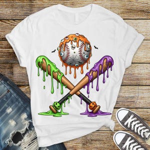 K&ouml;nnte beinhalten: Wei&szlig;es T-Shirt mit einem Halloween-Motiv. Die Grafik zeigt einen Baseball mit Aug&auml;pfeln, einem Spinnennetz und einem Totenkopf, gekreuzte Baseballschl&auml;ger mit gr&uuml;nem und lila Schleim und kleine K&uuml;rbisse.