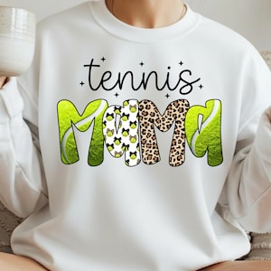 K&ouml;nnte beinhalten: Wei&szlig;es Sweatshirt mit dem Text "tennis Mama" in schwarzer Schrift und einem verspielten Design. Das Wort "Mama" zeigt ein Tennisball- und Leopardenmuster. Das Sweatshirt ist ein bequemer, l&auml;ssiger Stil.