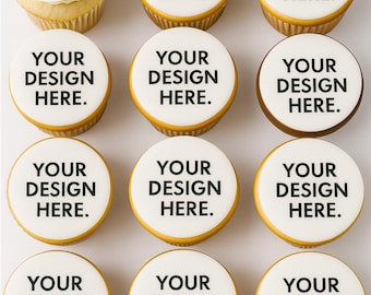 May include: A set of twelve cupcakes arranged in a grid. Eleven cupcakes feature a smooth white circular topper with the black text "YOUR DESIGN HERE." printed on each. One cupcake in the top left corner has a white swirled frosting top.