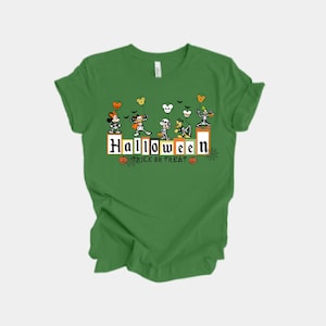Puede incluir: Camiseta verde con un diseño de Halloween. El diseño presenta personajes de dibujos animados y el texto "Halloween Trick or Treat". Incluye murciélagos, calabazas y siluetas inspiradas en Mickey Mouse.