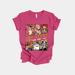 K&ouml;nnte beinhalten: Magentafarbenes T-Shirt mit einem Comic-Design von Toy Story-Charakteren in Halloween-Kost&uuml;men. Das Design zeigt Lotso, Woody und andere, mit dem Text "Toy Story EST. 1995".